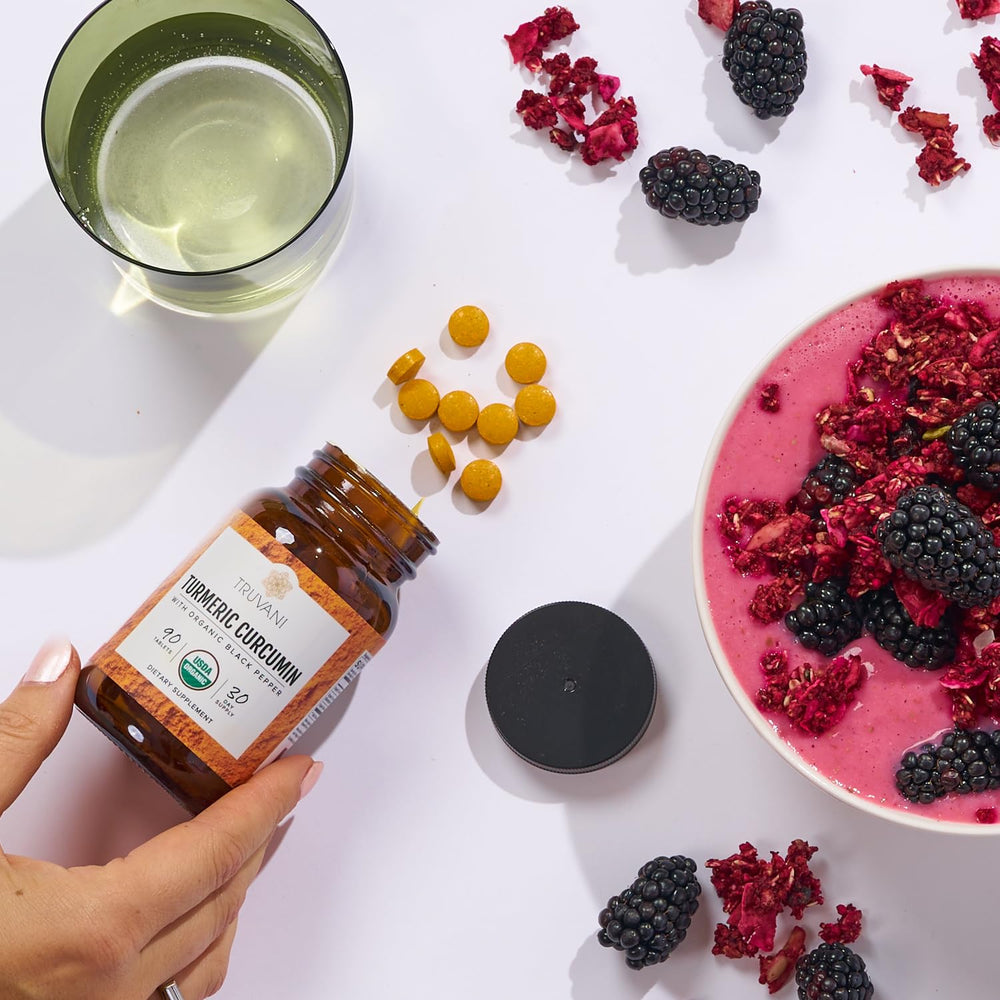Truvani Turmeric Curcumin tablets beside a cup, suggesting simple daily supplementation.