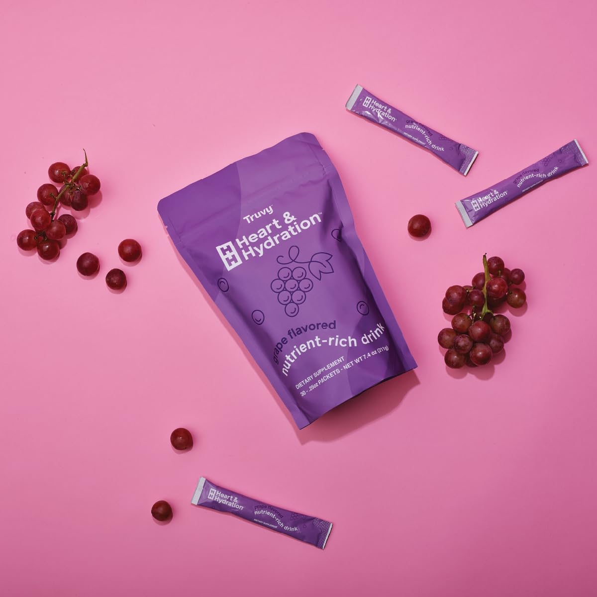 Stick packs dissolving in water for a refreshing grape drink.