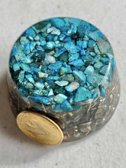 Turquoise Single Crystal Tower Buster Orgone Generator catching light in a workspace.