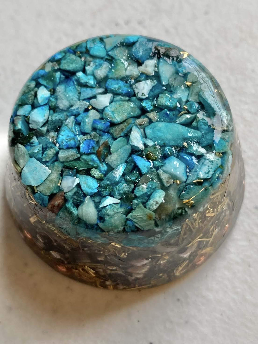 Turquoise Single Crystal Tower Buster Orgone Generator perched on a coffee table for balance.