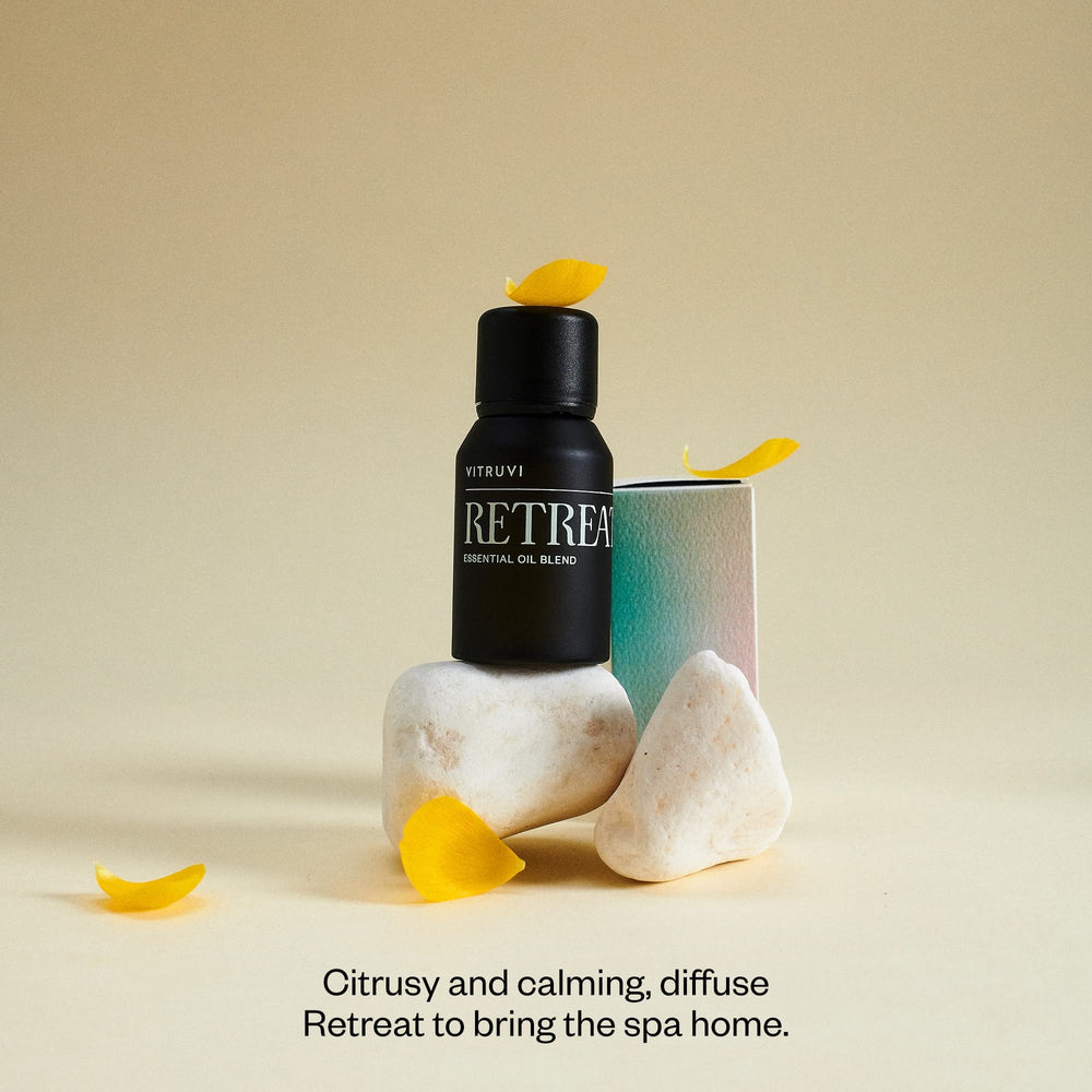 Bottle of Vitruvi Retreat with drops showing grapefruit and eucalyptus notes