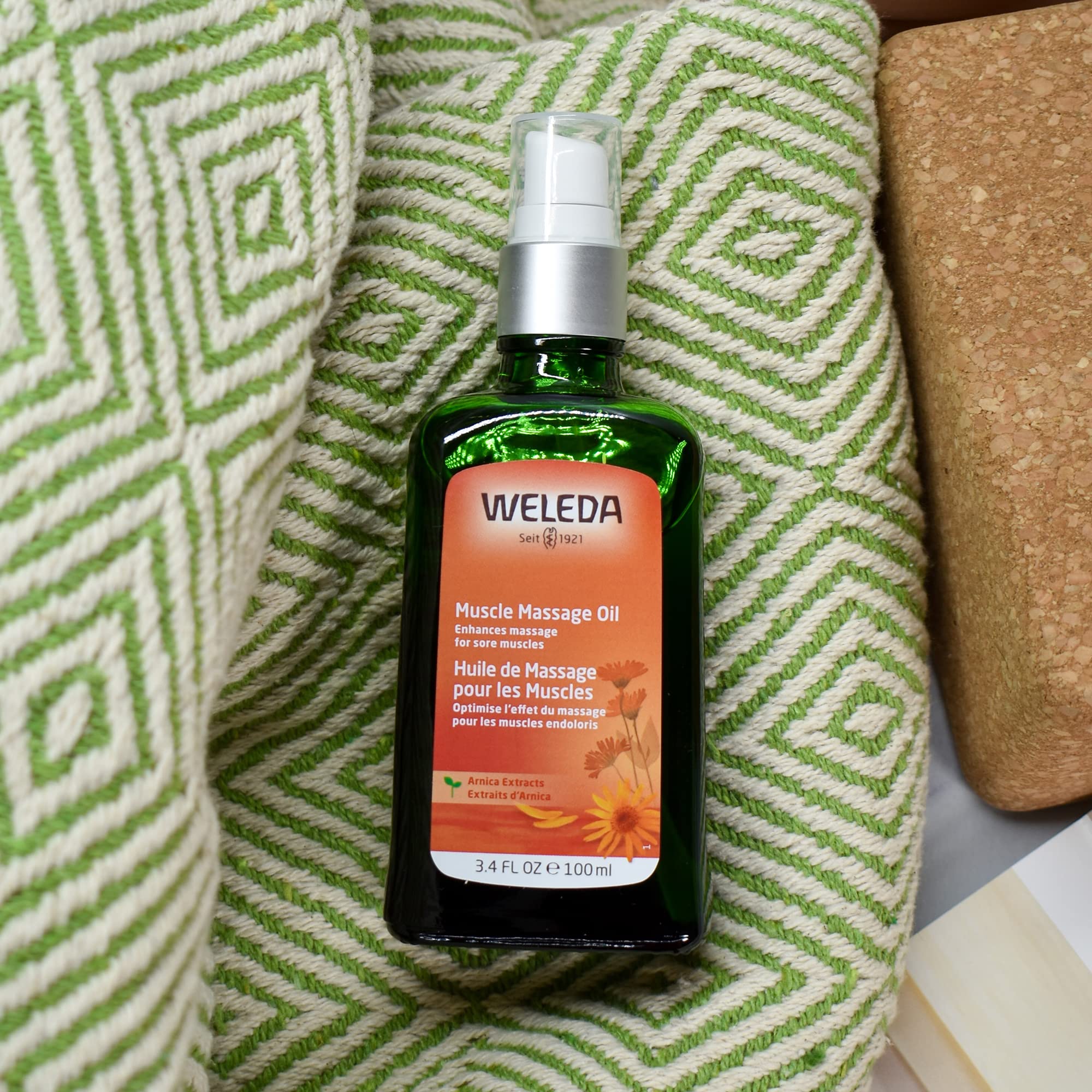 Weleda Arnica Muscle Massage Oil texture close-up highlights smooth plant-rich oil.