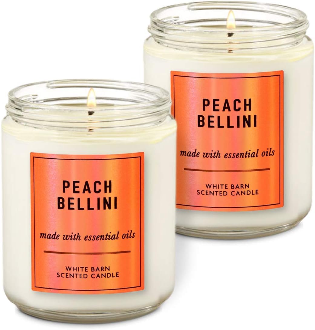 White Barn Peach Bellini candle 7 oz glowing warmly, delivering a relaxing aroma.