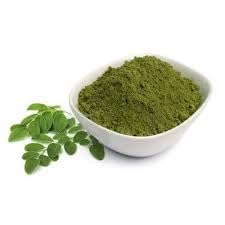 Pouring Moringa powder into a glass for a nutritious drink.