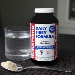 Scoop of Yerba Prima powder next to a glass showing convenient daily intake.